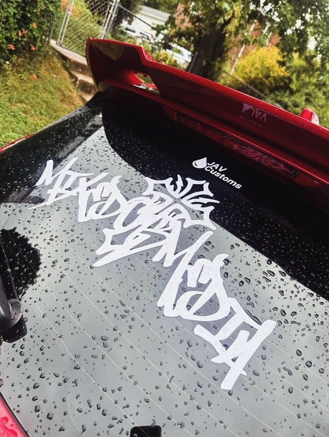 White graffiti-style vinyl lettering decal on a red car’s rear window