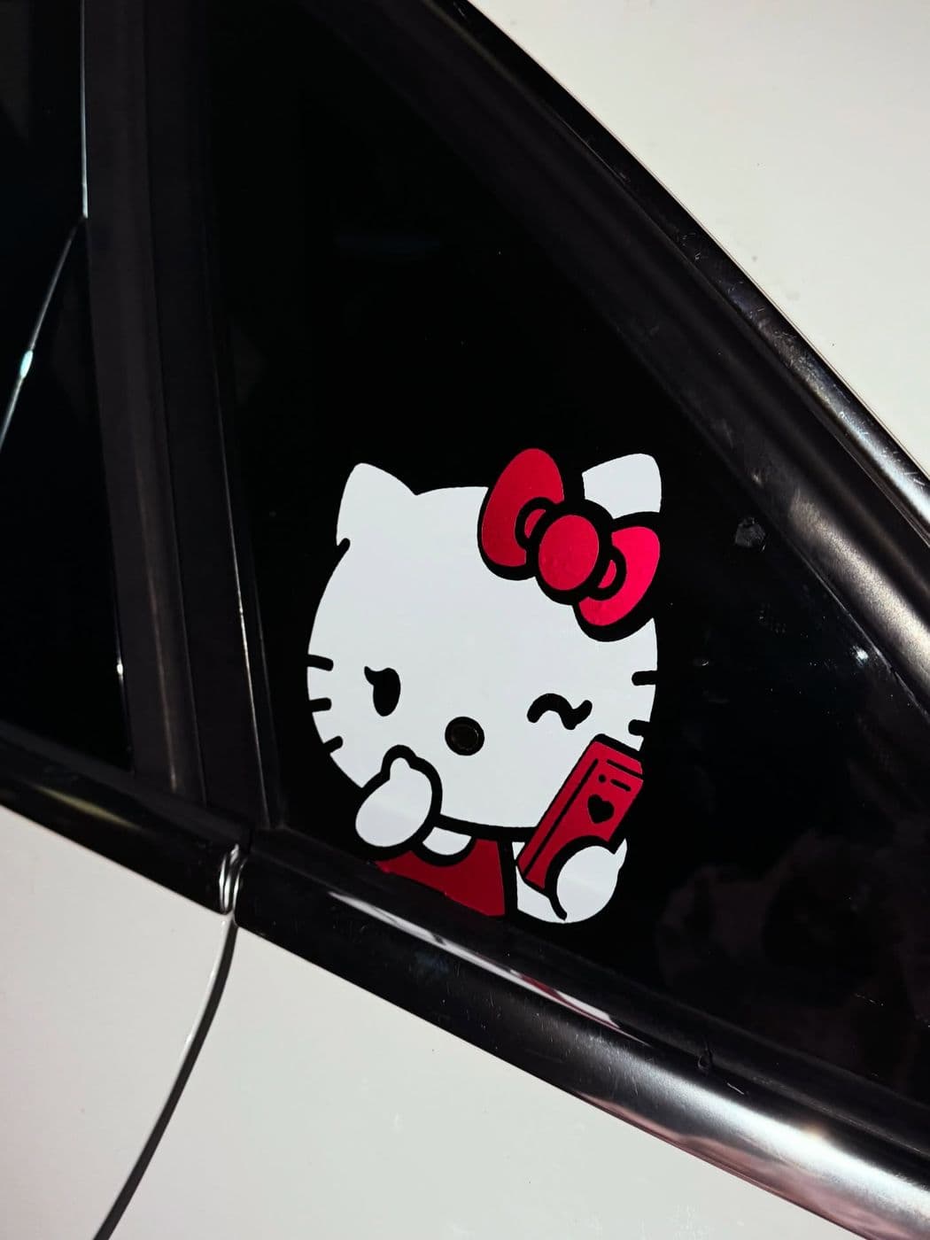 Full-color Hello Kitty–style decal on a car’s side window