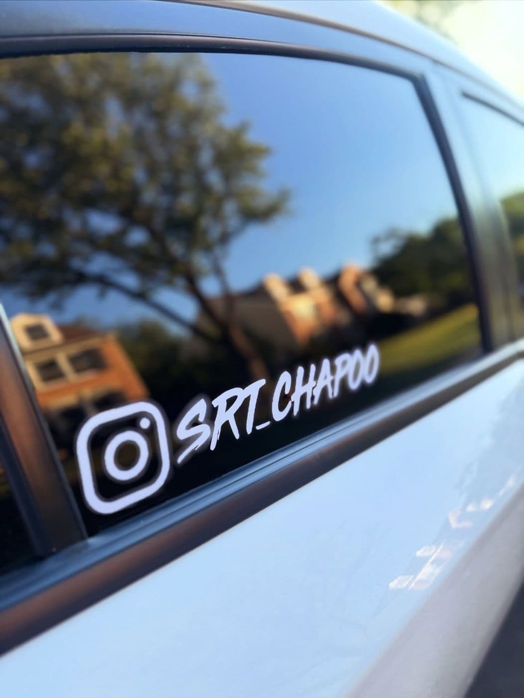 White Instagram handle decal on a white car’s rear side window