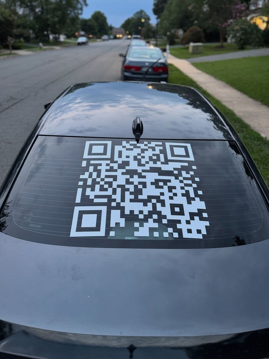 Large white QR code decal on a black car’s rear window