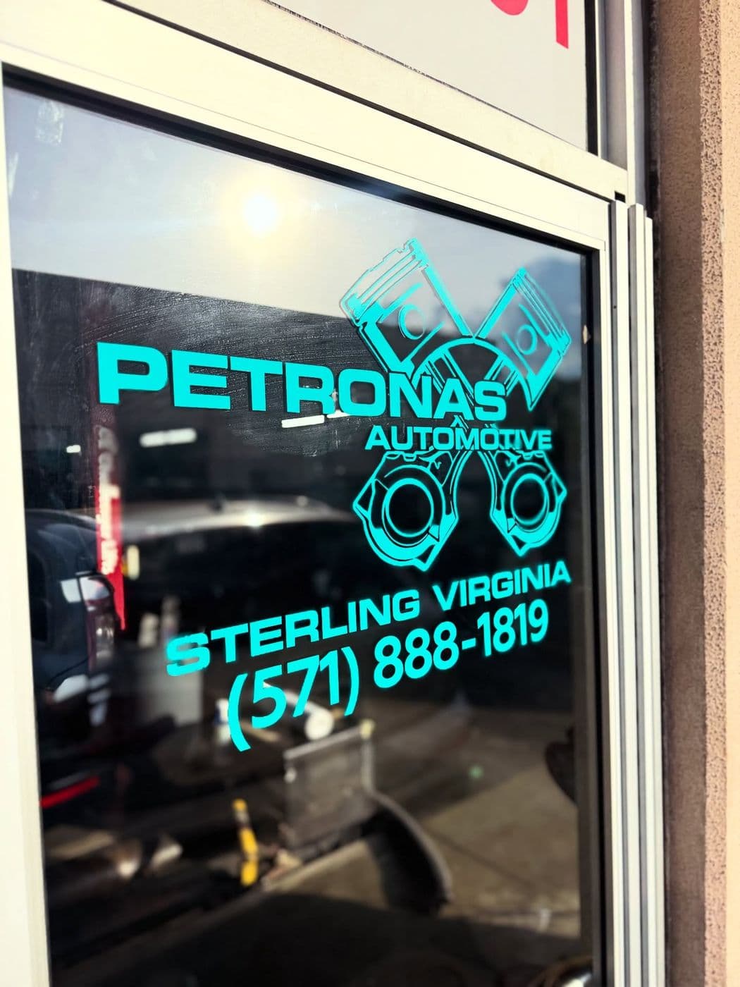 Teal vinyl Petronas Automotive lettering and logo on a business’s glass door