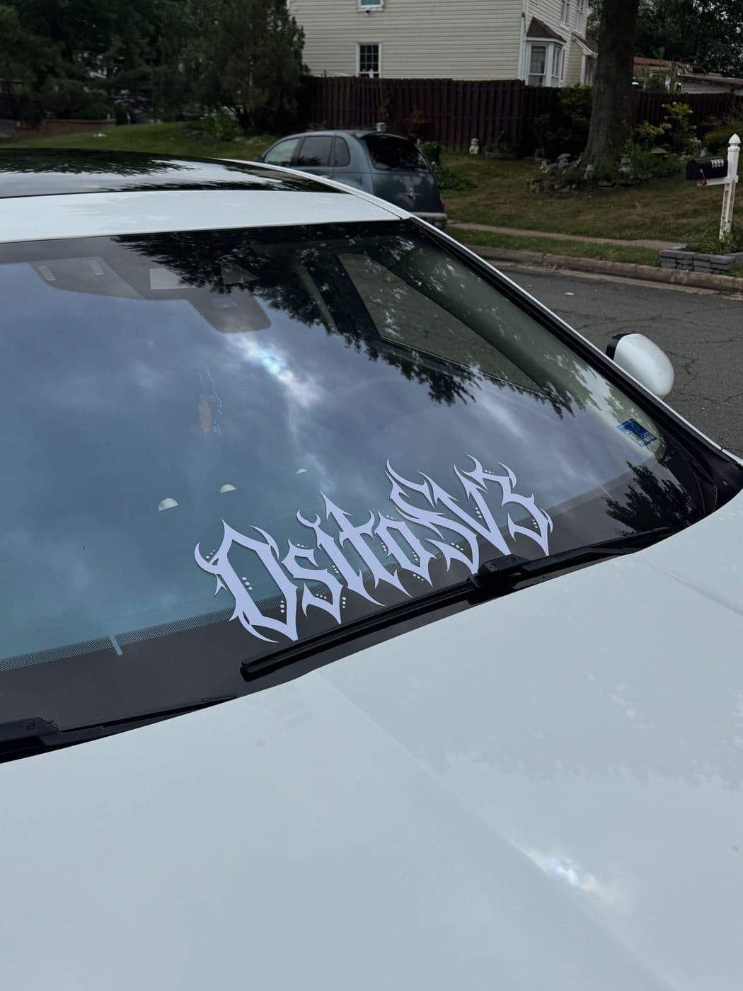 White windshield banner with custom lettering on a white car